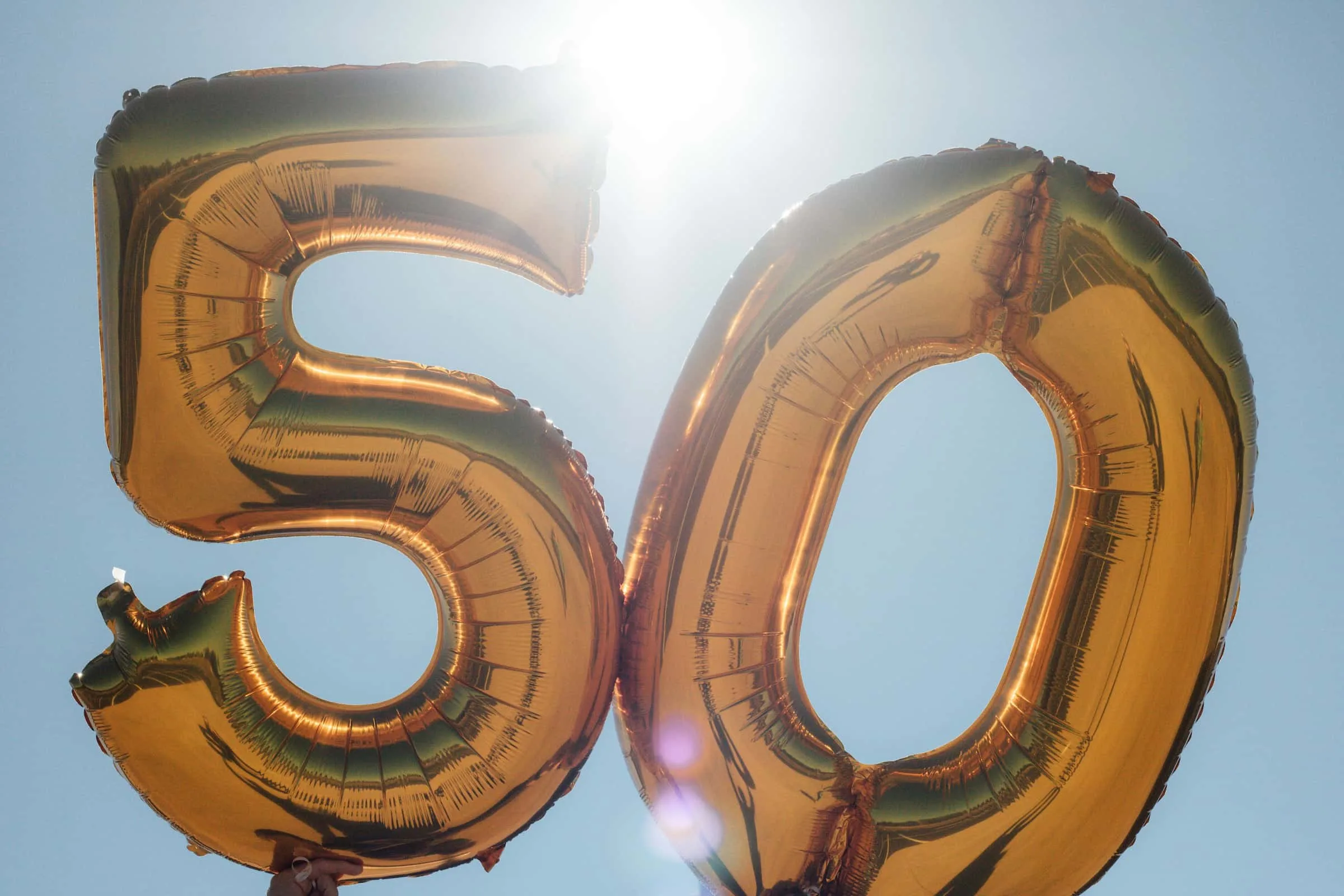 A photograph of balloon numbers against a sunlit sky. The numbers are 5- and 0- and are used to commemorate a fiftieth birthday.